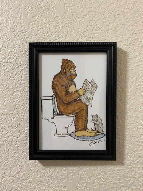 An illustration of Bigfoot sitting on a toilet reading a newspaper, with a cat sitting at their feet.