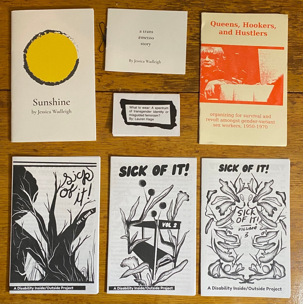 Seven zines on a wooden table.