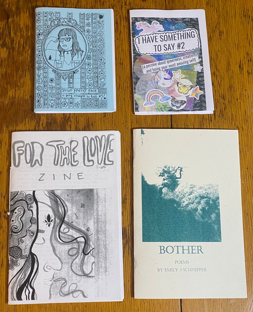 Four zines on a wooden table.