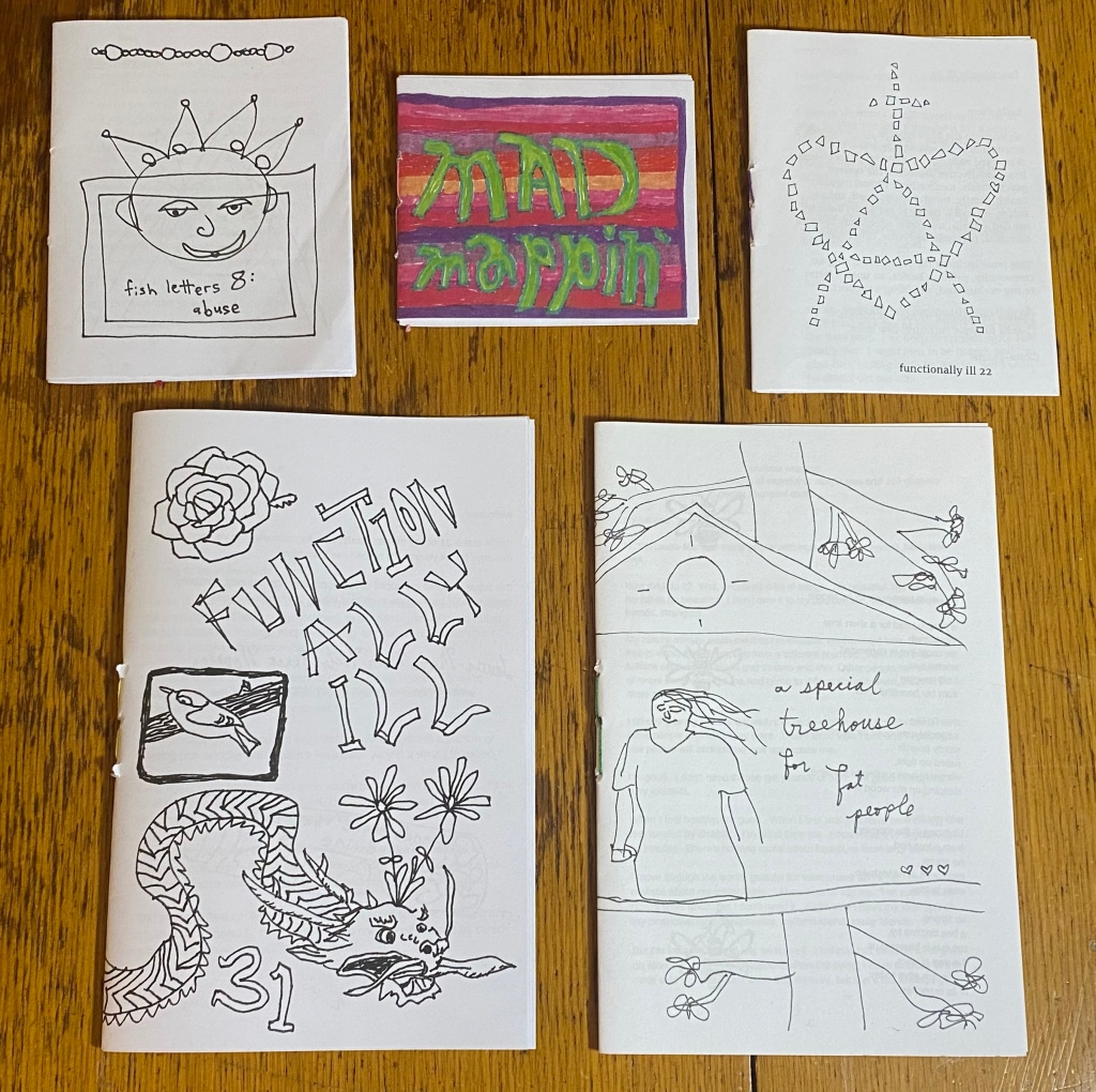 Five zines on a wooden table.